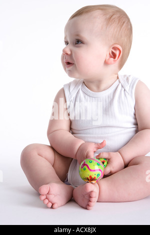 Baby boy sitting on the floor with a toy in his hand Stock Photo