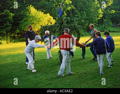 Family dancing around Maypole in Sweden during small traditional Midsummer celebration Stock Photo