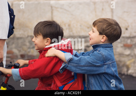 Editorial use only No model release two small smiling caucasian boys riding tandem on a bicycle without helmet in Taormina Stock Photo