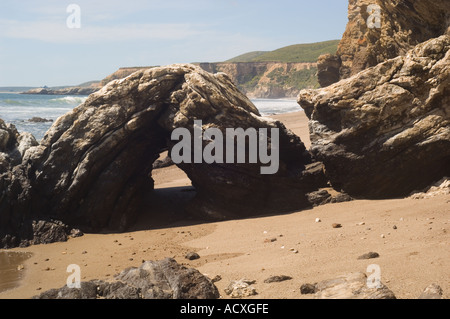 layered arch rock on Kellum Beach at Point Reyes National Seashore with cliffs and the ocean in the background Stock Photo