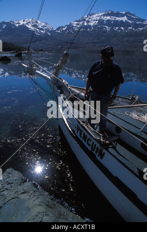 Boat with Captain on foredeck moored  in the Canal of the mountains in southern Chile, close to Puerto Natales Stock Photo