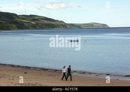 Couple walk along a sandy beach on the Black Isle, Inverness-shire, Scotland, UK Stock Photo