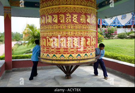 Children spinning a big prayer wheel. German Buddhist monastery. Lumbini. Nepal Stock Photo