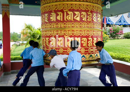 Children spinning a big prayer wheel. German Buddhist monastery. Lumbini. Nepal Stock Photo