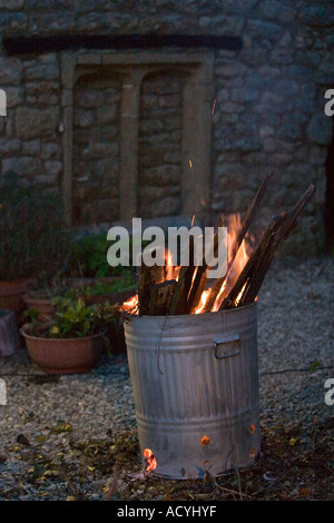 Zinc galvanised garden waste incinerator being used to burn old wooden floorboards High ISO Stock Photo