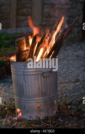 Zinc galvanised garden waste incinerator being used to burn old wooden floorboards High ISO Stock Photo
