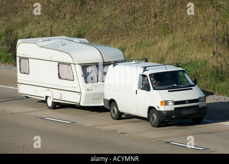 M25 motorway white van towing white caravan both clean unmarked with obscured number plate Stock Photo