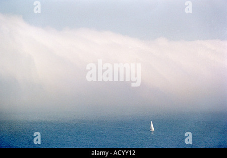 A lone yacht with a large bank of fog behind in Portland Harbour in Dorset England UK Stock Photo
