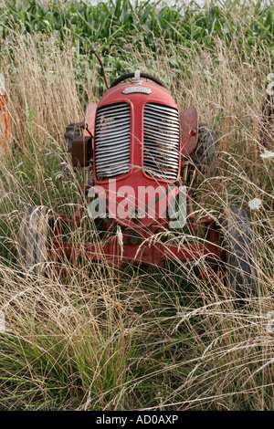 Old red farm tractor abandon in a field in France Stock Photo