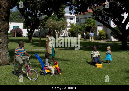 Local black African children with mother and white girl friend playing outside their homes in Accra Ghana West Africa Stock Photo