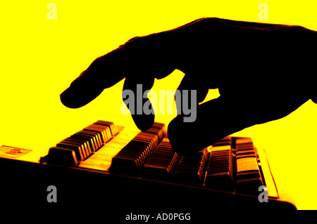 silhouette of hand on computer keyboard Stock Photo