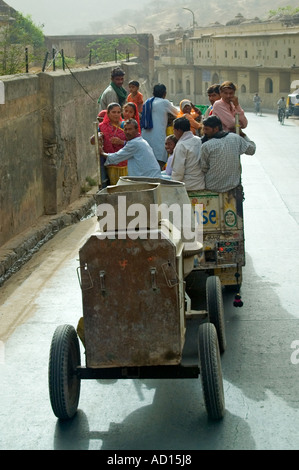 Vertical view of Indian men and women hitching a lift to work in the back of a dirty truck driving along the road. Stock Photo