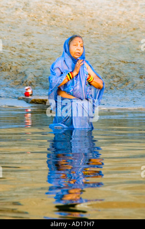 Vertical portrait of an Indian woman praying, semi submerged in the river Ganges. Stock Photo