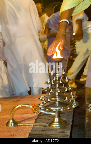 Vertical close up of hands passing through the flames of a tiered 'diyas' candelabram at the religious prayers 'aarti' Stock Photo