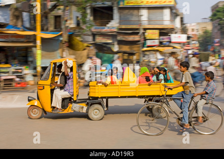 An auto rickshaw with passengers and bicycle with two boys in Varanasi.  Slow shutter speed and panning for motion blur. Stock Photo