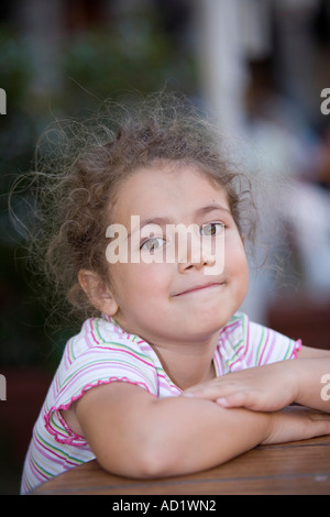 Sweet schoolgirl smiling with hands on the table Stock Photo