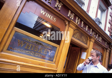 Young man drinking a guinness beer in front of the pub Mulligan s in Dublin Ireland Stock Photo