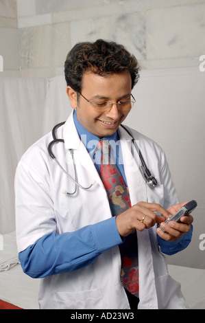 VEP72219 Young Indian Doctor smiling in white coat with stethoscope on mobile  phone Stock Photo
