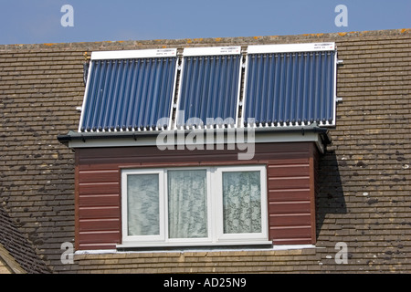 Three modern solar thermal evacuated tube panels on roof of detached house Cotswolds UK Stock Photo