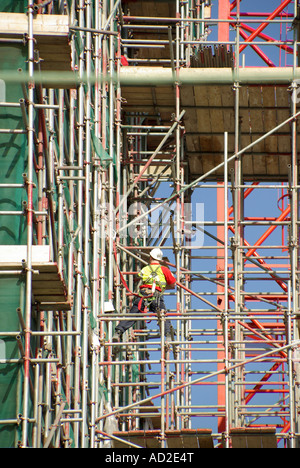 Scaffolder high vis jacket vest working on scaffold tubing construction building site  apartment block undergoing refurbishment East London England UK Stock Photo
