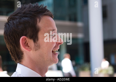 Young businessman looking up and smiling in the City of London Stock Photo