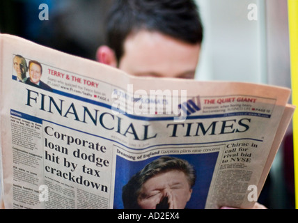 Young businessman reads Financial Times newspaper on London Underground tube train Stock Photo