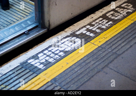 Open tube train door on London Underground platform with mind the gap sign on platform floor Stock Photo