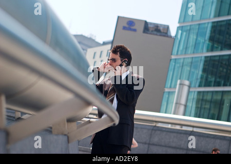 Young businessman rests on railing whilst using mobile phone in More London Place development near City Hall London Stock Photo