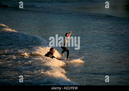 A young boy learns to surf in the evening light with his father at Manly beach Sydney Australia Stock Photo