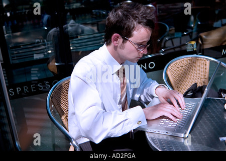 Young businessman looks at financial data on his laptop outside coffee shop in the City of London Stock Photo