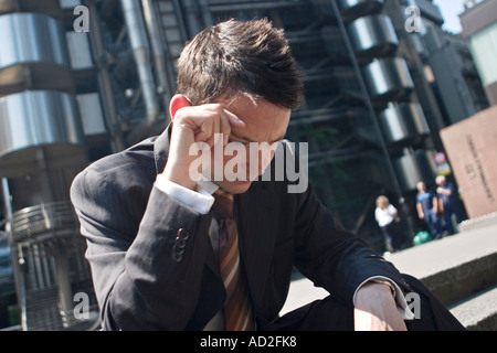 Young businessman puts hand to his head in the City of London in an open space Stock Photo