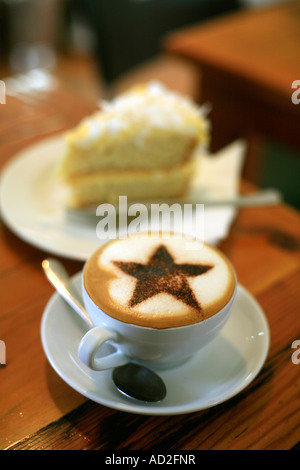 A Cappucino coffee with decorative chocolate star on top hummingbird cake in background Stock Photo
