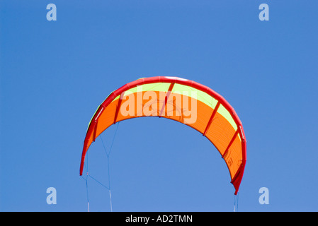 Large orange kite against bright blue sky Stock Photo