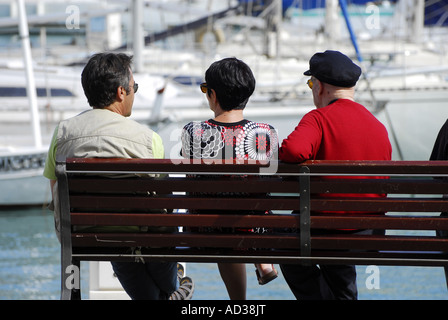 three friends sitting on park bench, cassis, france Stock Photo