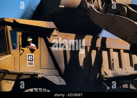 Front end loader pours dirt into a massive dump truck at a mine. Stock Photo