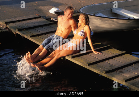 Young Swedish couple sitting on canal dock during summer in Stockholm Stock Photo