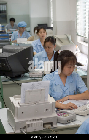 Production administration office in Chinese High Tech factory workers working at computers checking production records Stock Photo