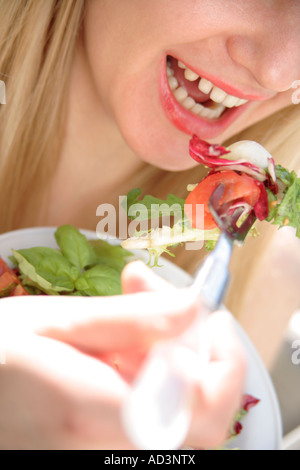 Young woman eating mixed salad, close up Stock Photo
