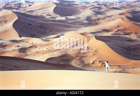 Young Woman Standing Among the Vast Sand Dunes of the Sahara Desert, Morocco Stock Photo