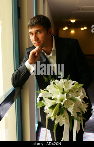 A portrait of a groom seen here on his wedding day in a traditional morning suit holding a bouquet of flowers. Stock Photo