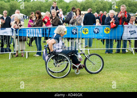 People cheering a disabled woman racing on a wheelchair Stock Photo