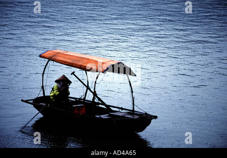 A row boat with red sun rain cover with a figure on the boat in a