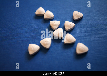 Triangle shaped ecstasy  tablets on a blue background. Stock Photo