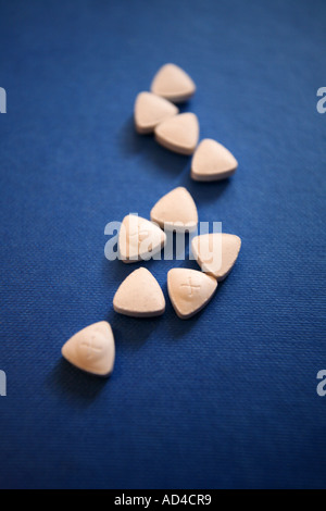 Triangle shaped ecstasy drug tablets on a blue background. Stock Photo