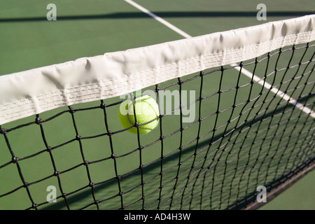 A tennis ball in mid-air next to a tennis net Stock Photo