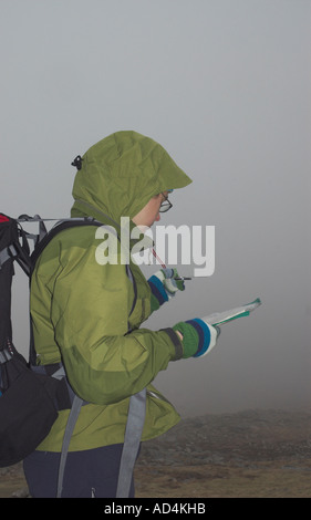 A walker taking bearings in the mist in Langdale area of the Lake District Cumbria UK Stock Photo