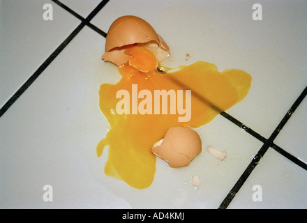 A broken egg on a tiled floor Stock Photo