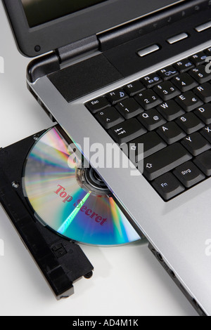 A CD stamped 'Top Secret' in the disc drive of a laptop computer Stock Photo