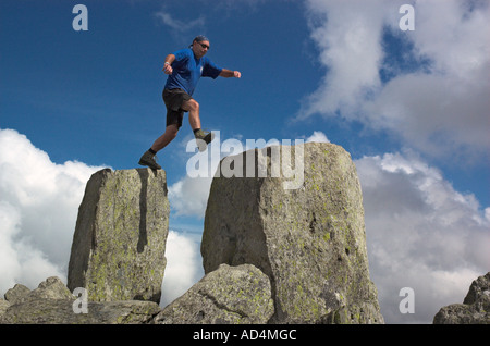 A climber jumping on Adam and Eve on the summit of Tryfan in Snowdonia North Wales Stock Photo