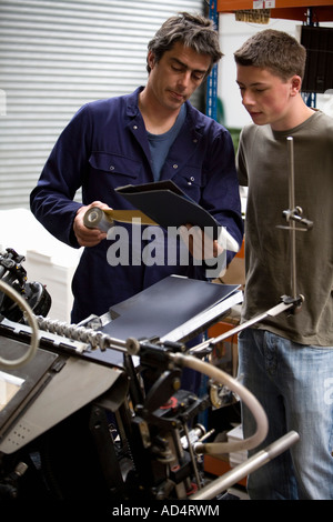A man training a young man in a printing factory Stock Photo
